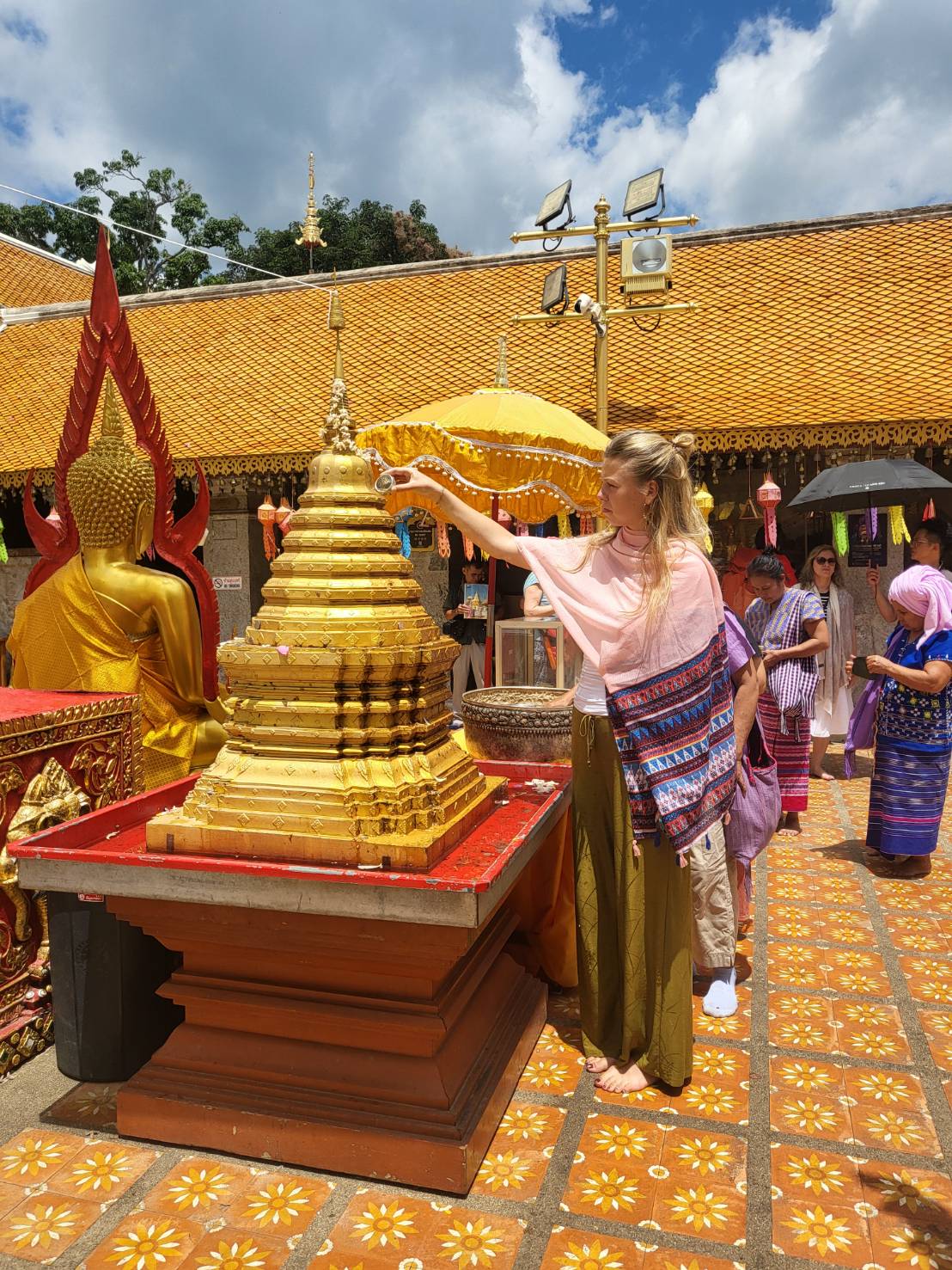Reiziger giet water over een gouden stoepa tijdens de cultuurweek in Chiang Mai